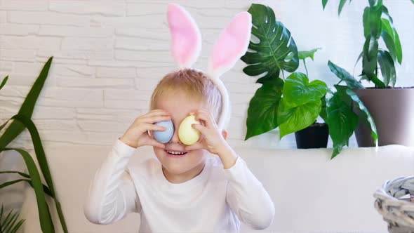 Funny happy child boy with easter eggs and bunny ears dancing alt