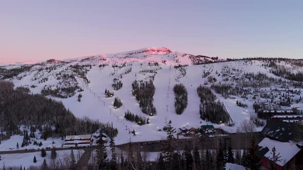 Drone captures Brians Head Ski Resort after sunset with snowboarders and skiers.