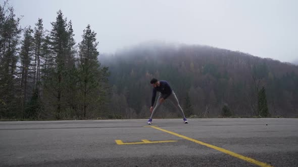 Strong and Flexible Man Stretching Before Training Session Outdoors in the Mountains alt