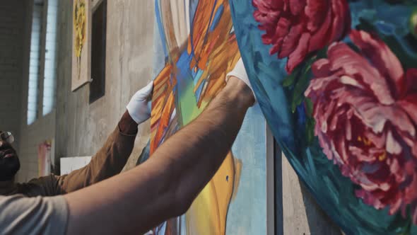 Two Men Hanging Painting on Wall alt