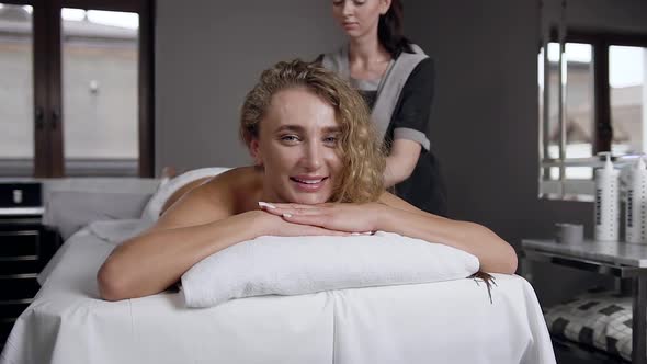 Smiling Charming Blond Woman which Relaxing During Body Massage in beauty center alt