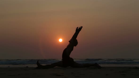 Man stretching at sandy beach in Goa at sunset. alt