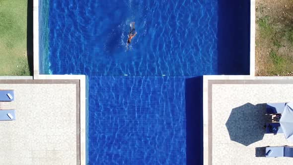 Aerial top view of Man in swimming pool from above alt