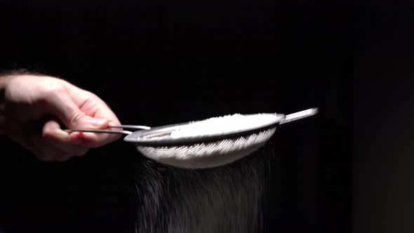 Chef Sifting Flour Through A Sieve To Prepare Delicious Dessert On A Black Background, Restaurant