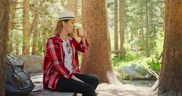 Slow Motion Thirsty Smiling Woman Sitting in Green Forest and Drinking Water alt