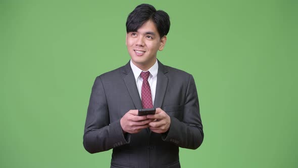 Young Handsome Asian Businessman Using Mobile Phone alt