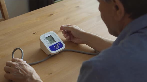 An elderly man measuring the blood pressure at home
