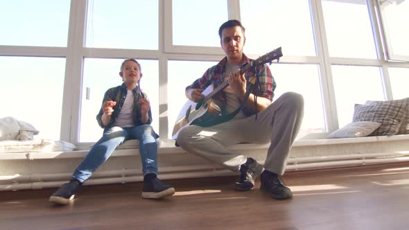 Dad and Daughter Sing a Song with an Acoustic Guitar alt