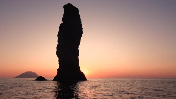 High Rock in Mediterranean Sea Against Horizon and Lipari Island. Colorful Sky, Summer Sunrise or alt