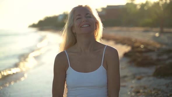 Slow motion of mature woman backlit on beach swinging her hair around from side to side eventually l alt