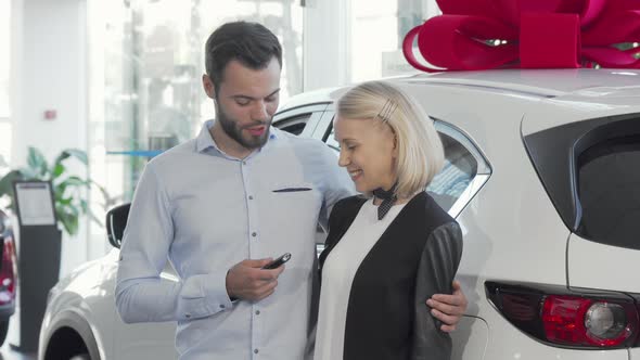 Happy Young Couple Standing Near Their New Car at the Dealership