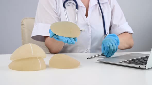 Plastic Surgeon Doctor Showing Silicone Implants to Patient alt