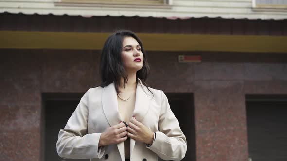 Portrait of Passionate Young Woman with Red Lips Corrects Coat in Pose Outdoor alt