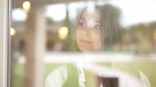 Young Woman Looking Through Closed Window