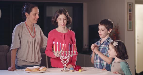 Kids and their mother lighting Hanukka candles alt