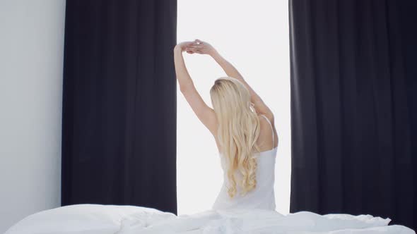 Young woman in the bed. Beautiful blond girl wakes up. Morning in the bedroom. alt