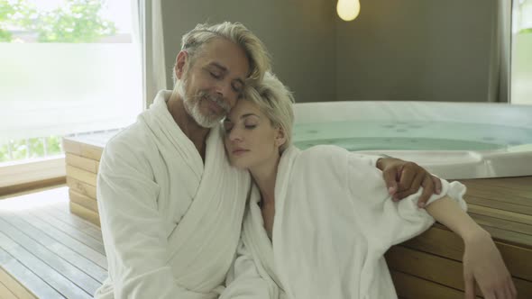 Couple in bathrobe relaxing near hot tub