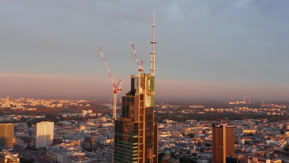 Orbit Around Shot of Top of Skyscraper Construction Site with Cranes Lit By Bright Morning Sun alt