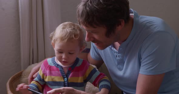Caucasian man with baby looking smartphone at home alt