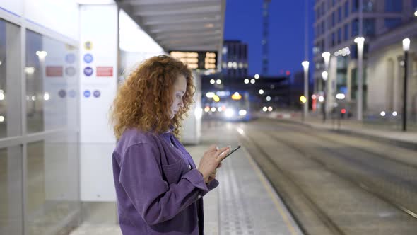Young woman waiting for train reading text messages