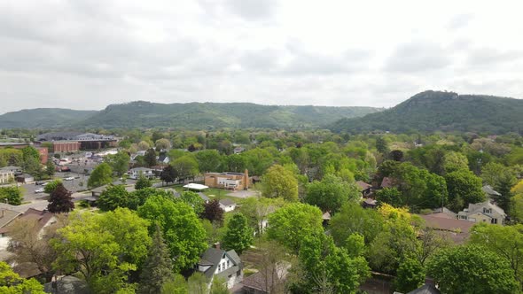 Flyover of residential neighborhood with mountain range covered in trees in Wisconsin.