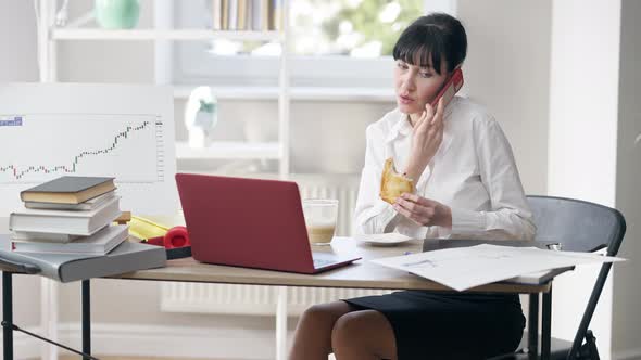Portrait of Successful Confident Woman Eating Lunch Hanging Up Phone and Messaging Online on Laptop alt