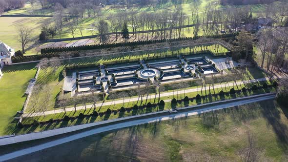 An aerial view over a large, upscale, luxury mansion on a sunny day. The drone camera truck right an alt