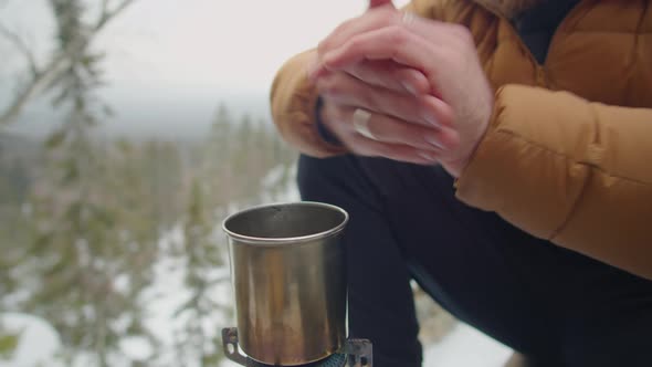 Man Warming near Gas Stove at Campsite on Winter Day alt