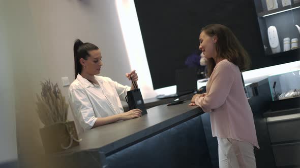 Reflection in Mirror Positive Smiling Shop Assistant Packing Jewellery Passing Shopping Bag to alt