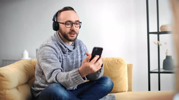 Casual Guy in Headphones Smiling Talking Online Video Call Smartphone alt