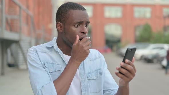 Outdoor African Man Having Loss on Smartphone alt
