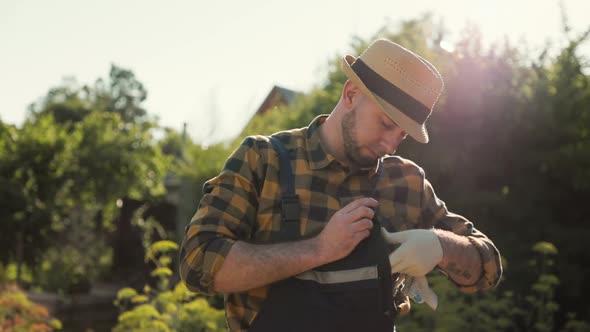Portrait of a bearded worker in a straw hat fastens the straps on a overalls. Slow motion alt