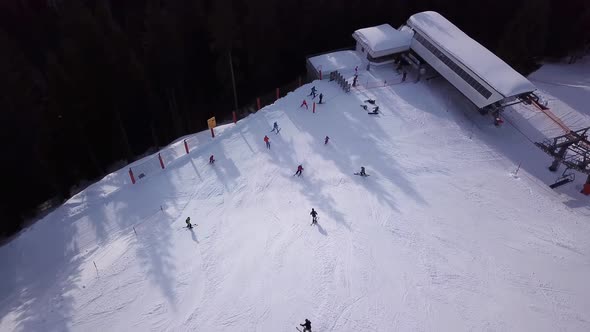 Aerial view of ski resort with people snowboarding down the hill. Stock footage. Flying over the ski alt