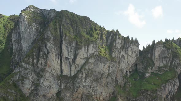 Drone flying towards and over high mountain top and revealing beautiful green valley alt