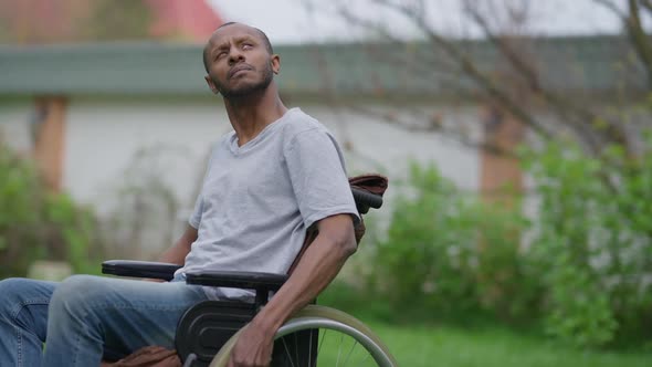 Live Camera Follows Serious Disabled Man Rolling Wheelchair in Spring Garden Looking Around alt