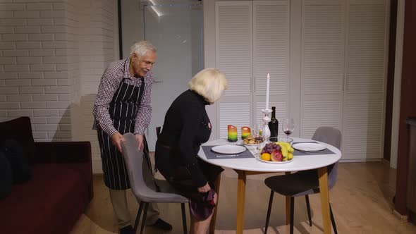 Senior Retired Couple Having Fun During Romantic Supper in the Kitchen Celebrating Their Anniversary alt