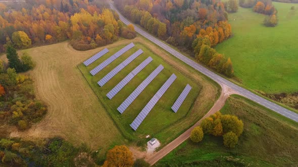Aerial view of solar panel rows near a forest during Autumn, Estonia. alt