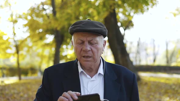 Man Having Pleasure When Listening to the Music Through the Earphones in Park alt