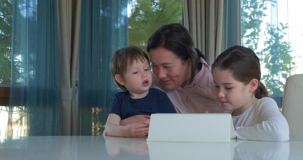 Grandma Entertaining Her Little Grandchildren with a Tablet Computer Game