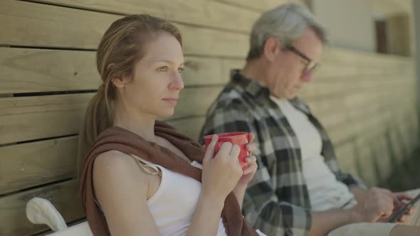 Woman sitting outside of cabin drinking coffee