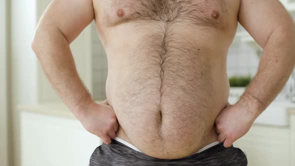 Shirtless Overweight Man with Hairing Stomach Scratching His Tummy Front View