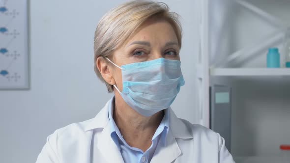 Serious Female Doctor in Face Mask Looking at Camera, Concerned About Epidemic