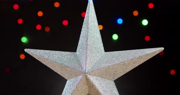 Shiny Christmas Star on a Black Background with Colorful Lights