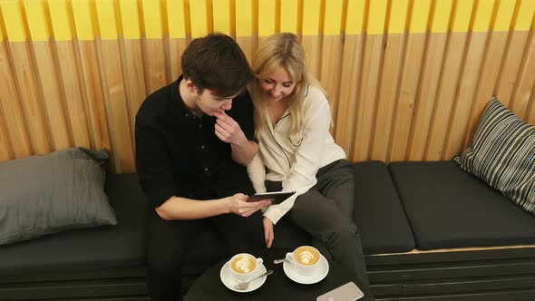 Young Couple Looking at Tablet and Drinking Coffee alt
