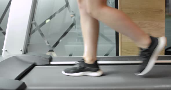 Closeup Athletic Feet Running on Treadmill in Fitness Gym