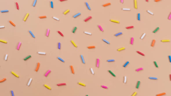 A Rotation Background of Sprinkles for Sweets on a Beige Background
