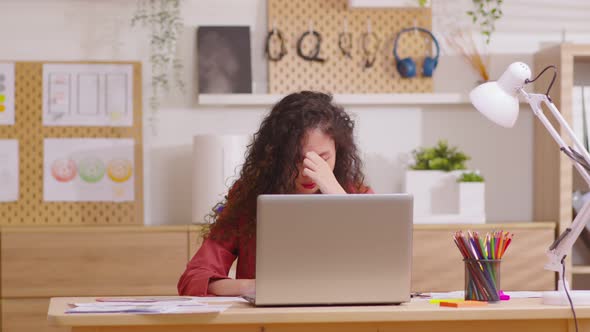 Asian woman sitting at desk in front of laptop stressed out face and headache shows her stressful alt