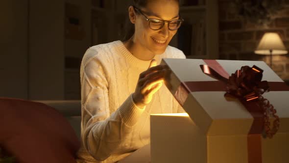 Young happy woman opening a beautiful Christmas gift