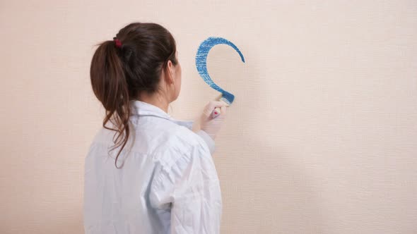 Creative Artist in Shirt Draws Heart with Blue Paint on Wall alt