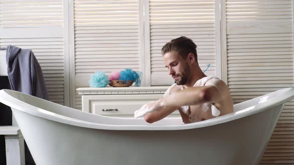 Confident Guy with Shaver in Bathroom. Bath Concept. Young Guy Bathing in the Bath in Bathtube. Gay alt